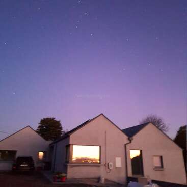 The image depicts a serene scene of two houses with gabled roofs, set against a starry sky at dusk, with a car parked in the driveway.