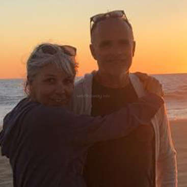 The image depicts a man and woman embracing on a beach at sunset, with the ocean and sky visible in the background, and a watermark reading \"workaway.info\".
